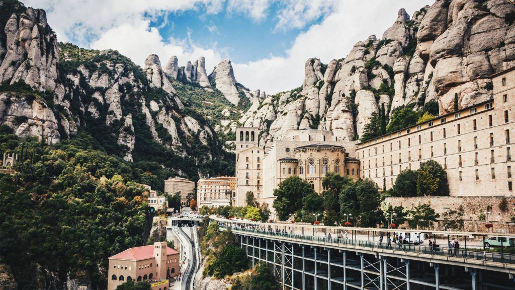 Das beeindruckende Kloster Montserrat, eingebettet in die zerklüfteten Berge von Katalonien, Spanien, mit Touristen, die die Anlage erkunden.
